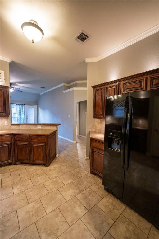 kitchen with tasteful backsplash, black fridge, ceiling fan, crown molding, and light tile patterned flooring