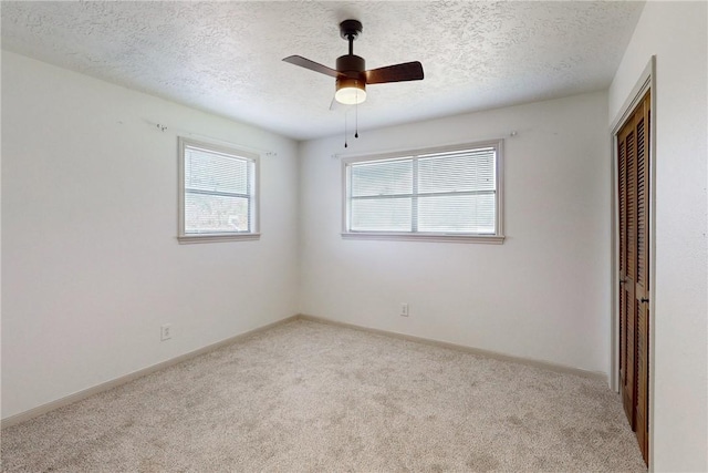 carpeted empty room featuring a textured ceiling and ceiling fan