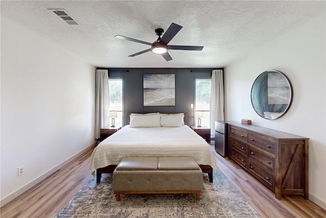 bedroom featuring a textured ceiling, light wood-type flooring, and ceiling fan