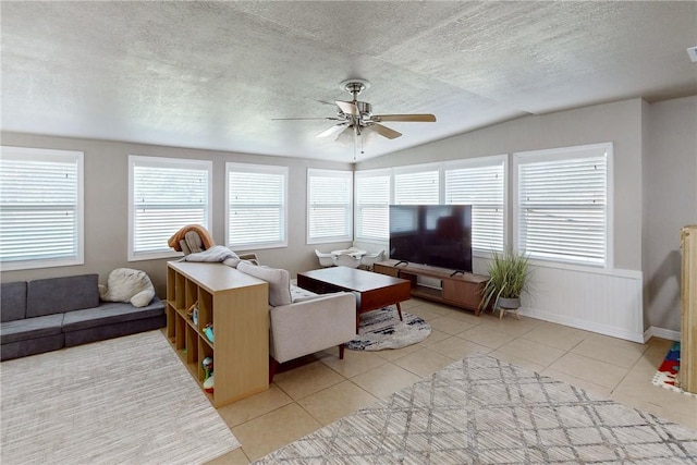 living room featuring light tile patterned floors, a textured ceiling, ceiling fan, and lofted ceiling