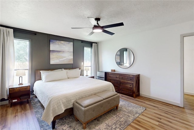 bedroom with multiple windows, ceiling fan, a textured ceiling, and hardwood / wood-style flooring