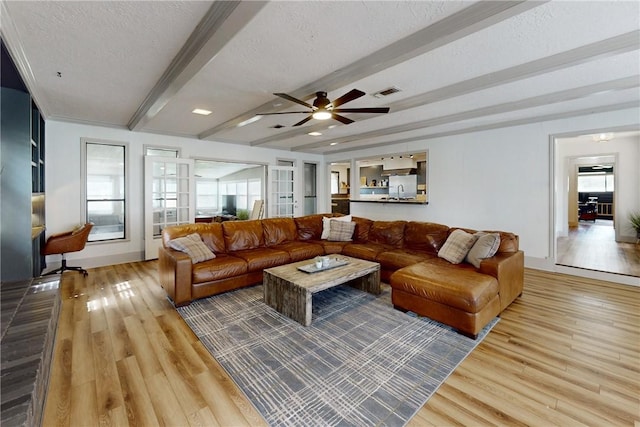 living room with french doors, a textured ceiling, ceiling fan, beam ceiling, and wood-type flooring