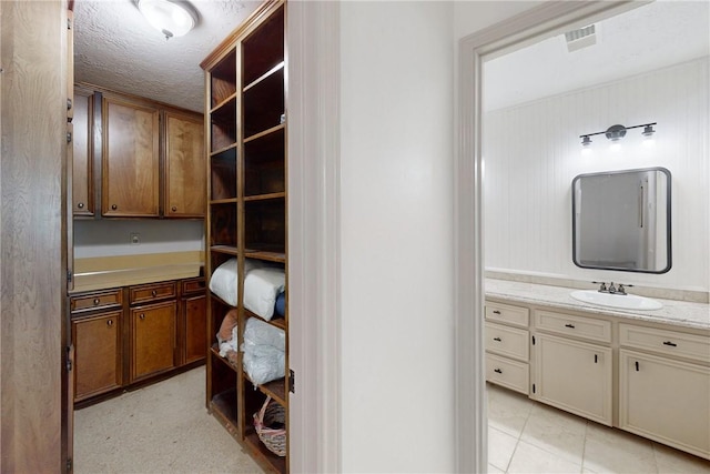 bathroom with tile patterned flooring, vanity, and a textured ceiling