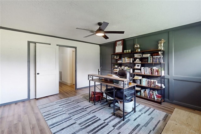 office with ceiling fan, wood-type flooring, a textured ceiling, and ornamental molding