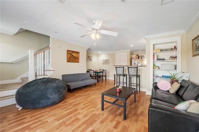 living room with stairs, a ceiling fan, ornamental molding, and wood finished floors