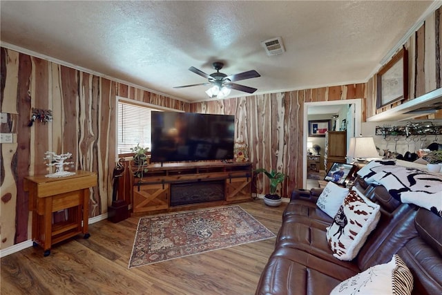 living room with wood-type flooring, a textured ceiling, ceiling fan, and wood walls