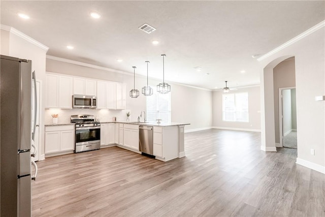 kitchen with kitchen peninsula, pendant lighting, stainless steel appliances, and white cabinetry