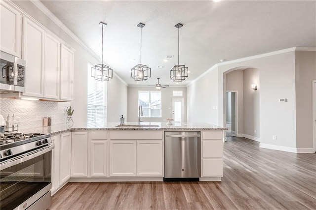 kitchen with appliances with stainless steel finishes, ceiling fan, sink, decorative light fixtures, and white cabinetry