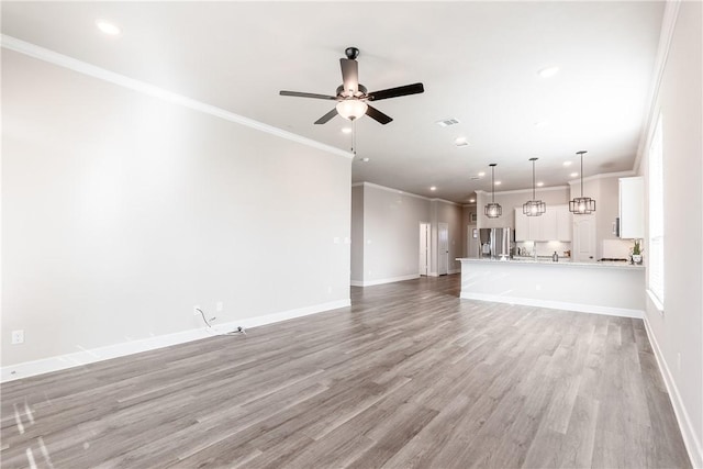 unfurnished living room featuring ceiling fan, light wood-type flooring, and crown molding