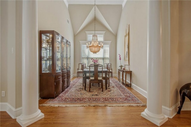 dining space featuring decorative columns, hardwood / wood-style flooring, and an inviting chandelier