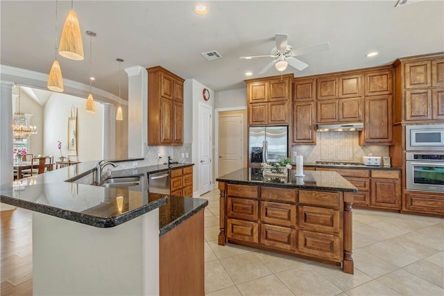 kitchen featuring appliances with stainless steel finishes, hanging light fixtures, crown molding, and a kitchen island with sink