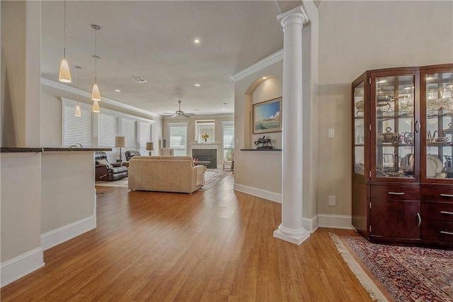 living room featuring ornate columns, ceiling fan, crown molding, and light wood-type flooring