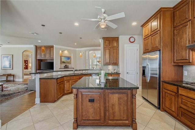 kitchen featuring stainless steel fridge, ornamental molding, decorative light fixtures, a kitchen island, and kitchen peninsula