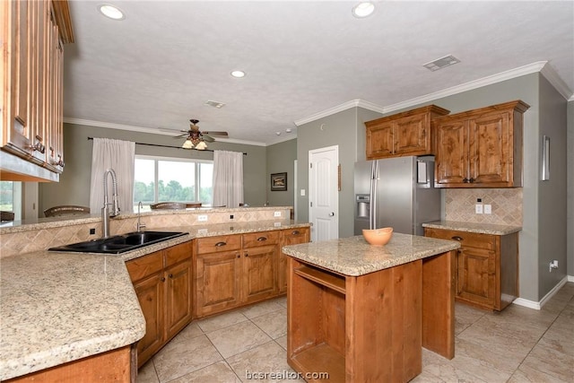 kitchen with ceiling fan, crown molding, sink, stainless steel fridge with ice dispenser, and a kitchen island