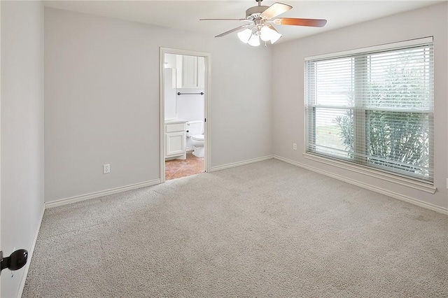 unfurnished bedroom featuring ensuite bathroom, light colored carpet, and ceiling fan