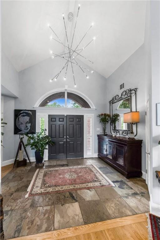 entryway with a chandelier, baseboards, and high vaulted ceiling