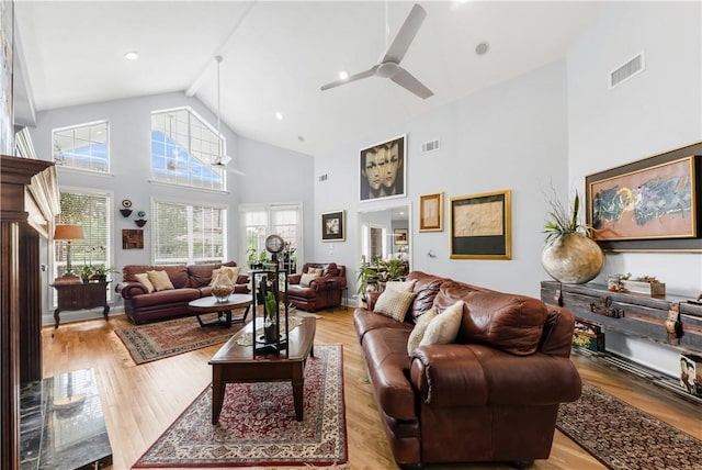 living area featuring light wood-type flooring, visible vents, and high vaulted ceiling