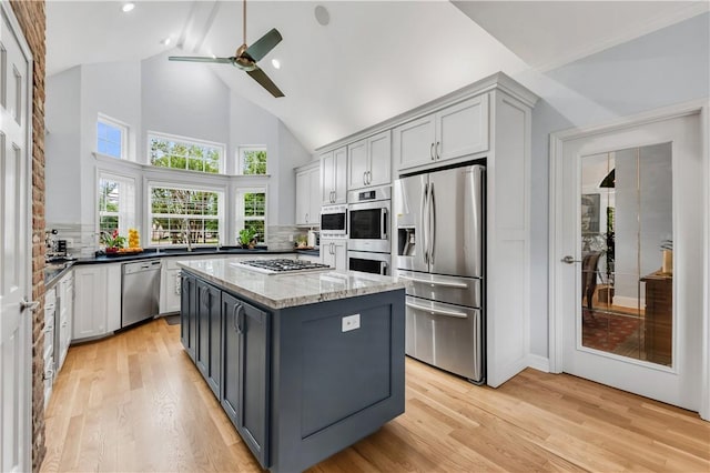 kitchen with light wood finished floors, stainless steel appliances, decorative backsplash, and ceiling fan