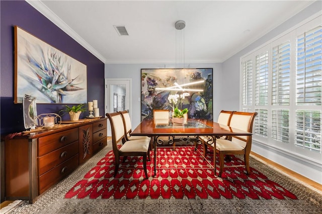 dining room with ornamental molding, visible vents, plenty of natural light, and wood finished floors