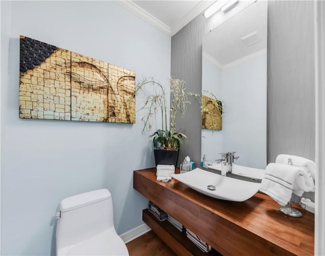 half bathroom featuring toilet, baseboards, ornamental molding, vanity, and wood finished floors