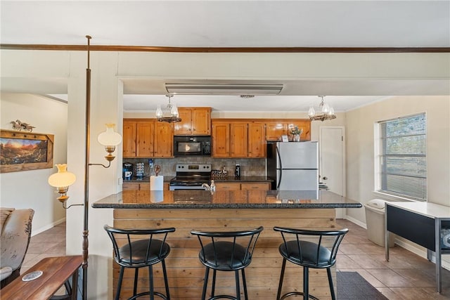 kitchen featuring decorative backsplash, appliances with stainless steel finishes, hanging light fixtures, and a breakfast bar area