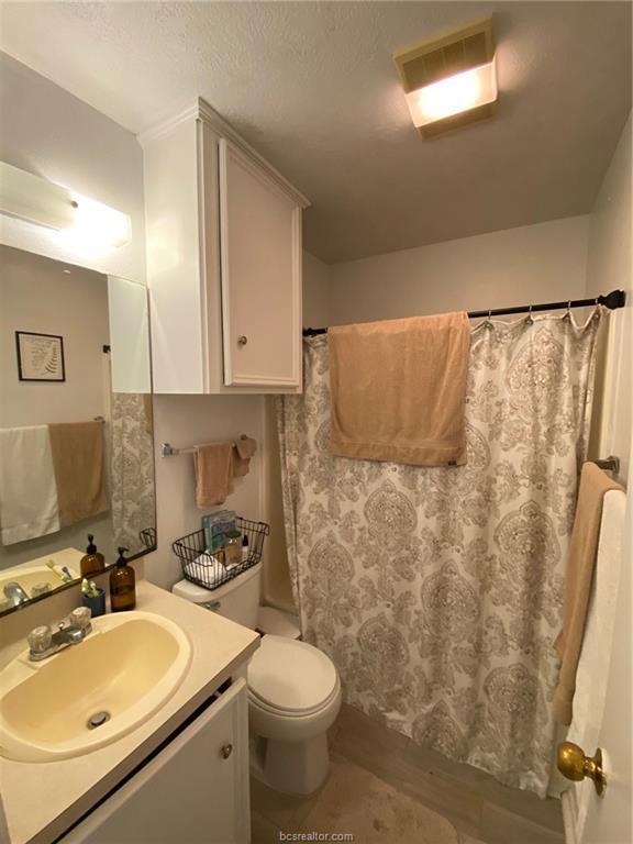 bathroom featuring vanity, a shower with shower curtain, hardwood / wood-style flooring, toilet, and a textured ceiling