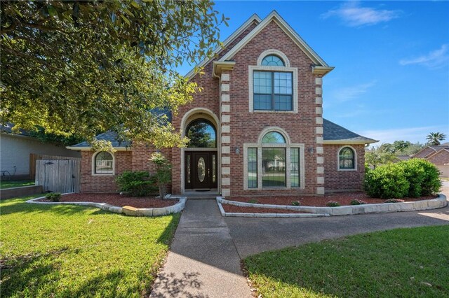 traditional home with a front yard and brick siding