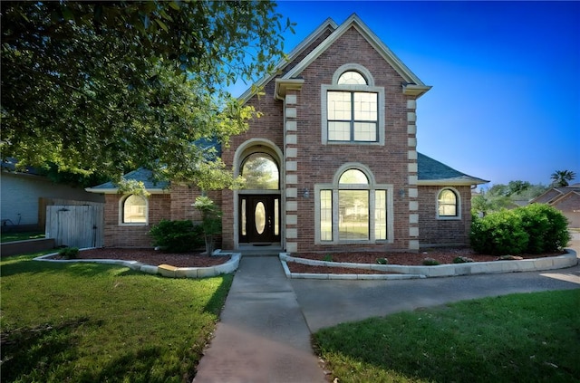 traditional home featuring a front yard and brick siding