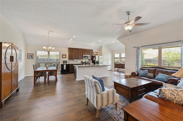 living room featuring ceiling fan with notable chandelier, a healthy amount of sunlight, lofted ceiling, and dark wood-type flooring