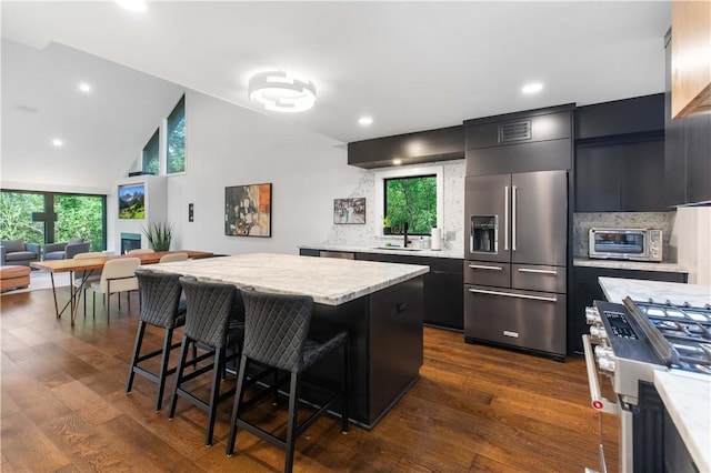 23 Forest Dr, College Station, TX 77840 - kitchen featuring high quality appliances, light countertops, dark cabinetry, a breakfast bar, and tasteful backsplash