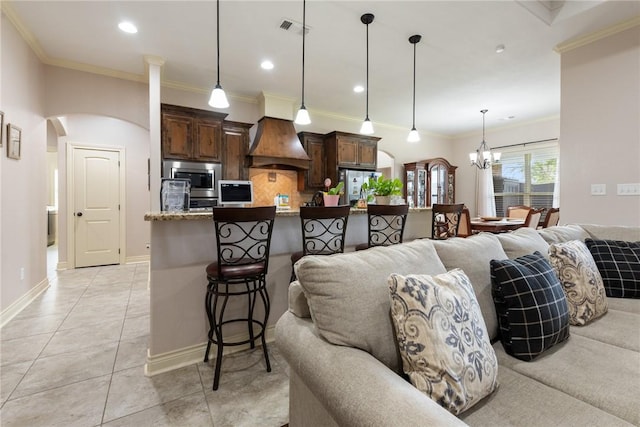 kitchen with appliances with stainless steel finishes, backsplash, decorative light fixtures, stone counters, and a breakfast bar area