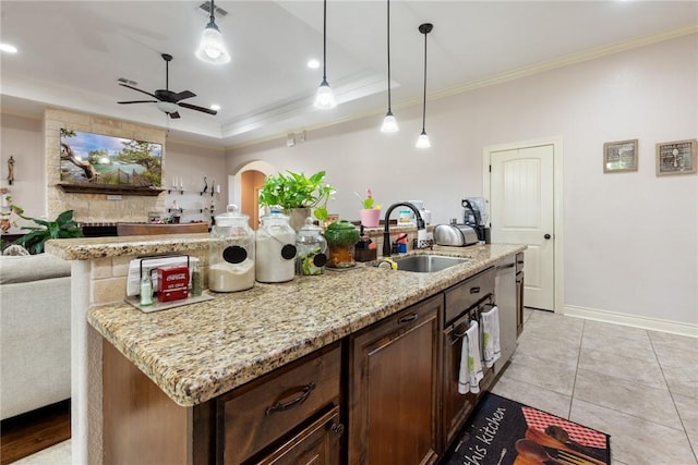 kitchen featuring sink, hanging light fixtures, a raised ceiling, crown molding, and an island with sink