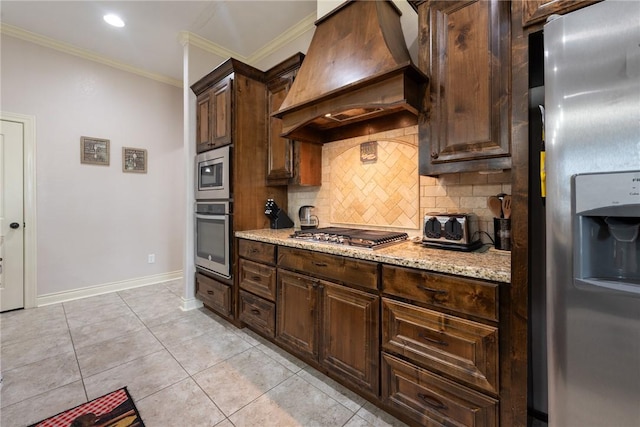 kitchen with light stone countertops, custom range hood, crown molding, and appliances with stainless steel finishes