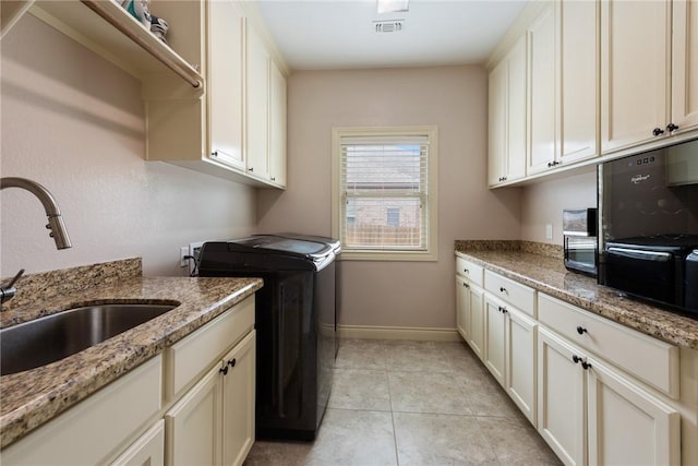 laundry area with washer and clothes dryer, sink, light tile patterned flooring, and cabinets