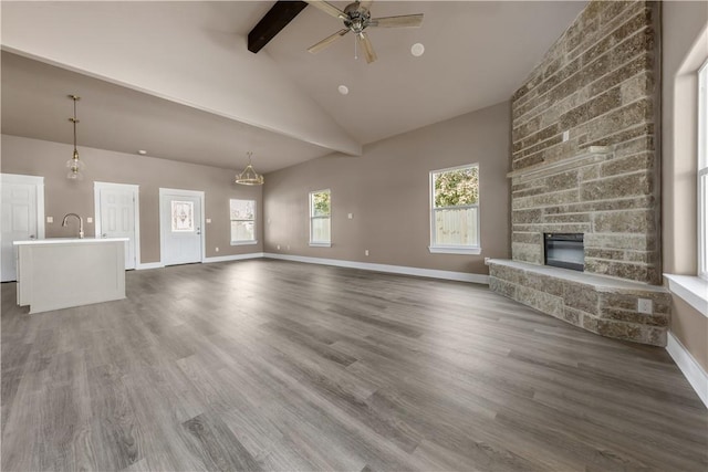 unfurnished living room featuring beam ceiling, dark hardwood / wood-style flooring, high vaulted ceiling, and a fireplace