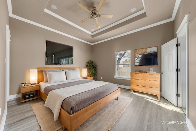 bedroom with light hardwood / wood-style floors, a raised ceiling, and ceiling fan