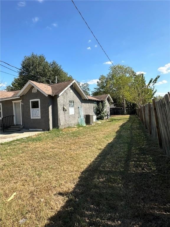 view of side of home with a lawn and central air condition unit