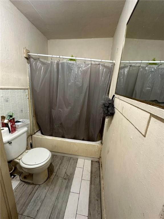 bathroom featuring backsplash, shower / tub combo, and toilet