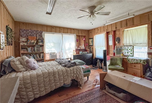 403N Banks St, Caldwell, TX 77836 - bedroom with wooden walls, light wood-style floors, a textured ceiling, and a ceiling fan