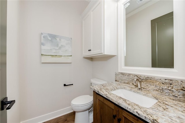 bathroom with vanity, toilet, wood finished floors, and baseboards