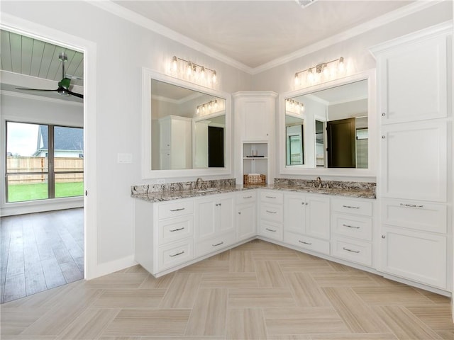 bathroom with double vanity, ornamental molding, baseboards, and a sink