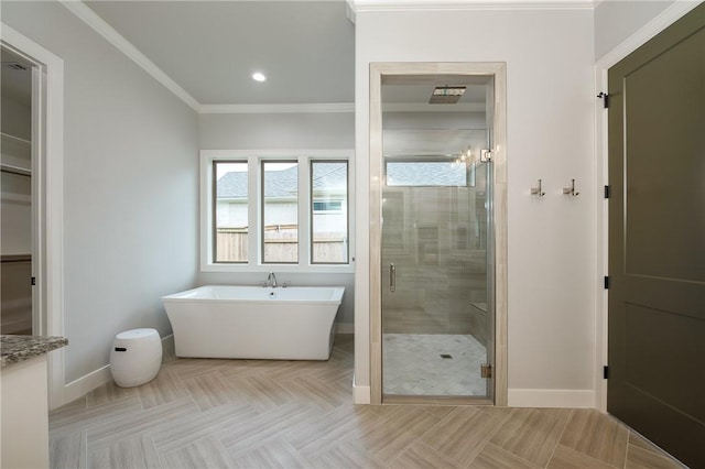 bathroom featuring a stall shower, crown molding, baseboards, and a freestanding tub