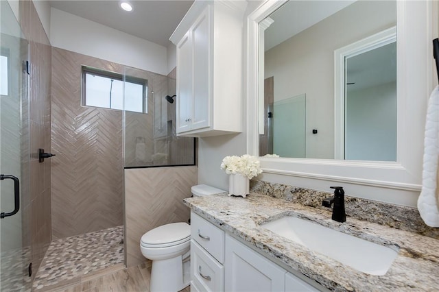 full bathroom featuring a stall shower, toilet, and vanity