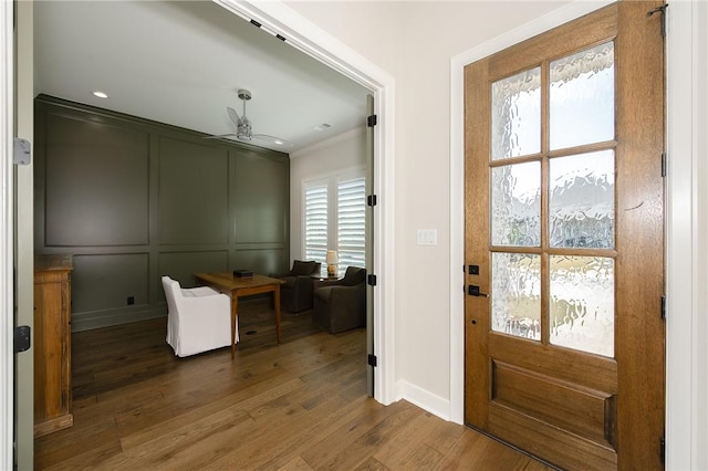 entryway featuring a ceiling fan, wood finished floors, ornamental molding, and a decorative wall