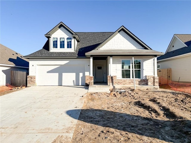 craftsman-style house with a garage, fence, concrete driveway, and brick siding