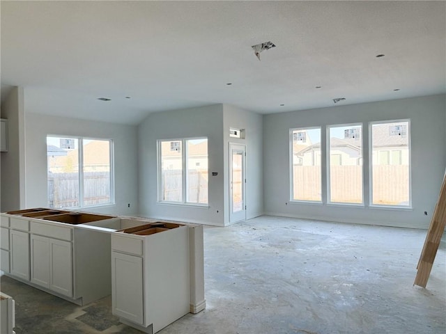 kitchen featuring concrete flooring, a center island, and white cabinets