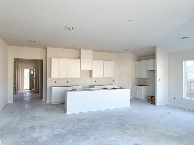 3108 Charge Ln, Bryan, TX 77808 - kitchen with a wealth of natural light, a center island, white cabinets, and unfinished concrete flooring
