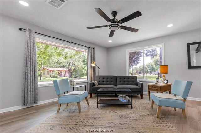 living room with light hardwood / wood-style flooring, ceiling fan, and a healthy amount of sunlight