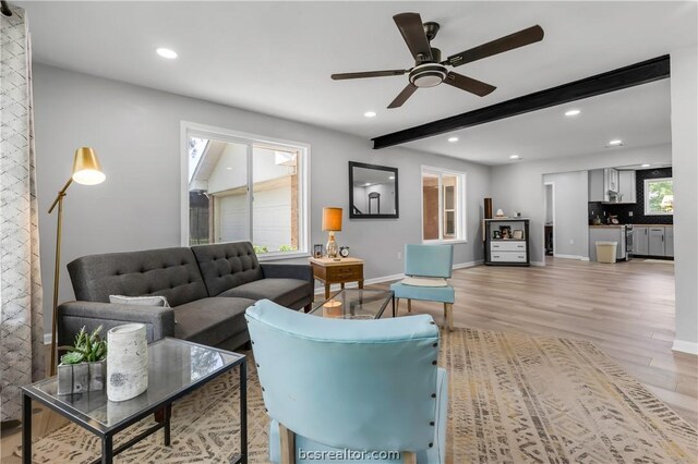 living room with beam ceiling, light wood-type flooring, plenty of natural light, and ceiling fan