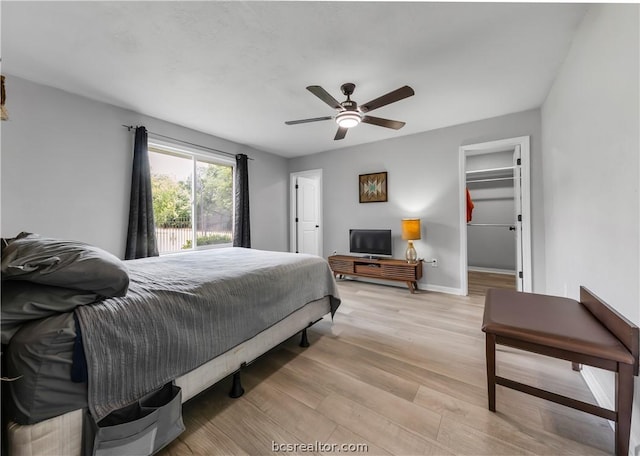 bedroom with a spacious closet, a closet, light hardwood / wood-style flooring, and ceiling fan